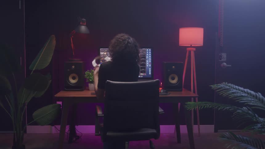 Woman sitting in front of a computer in a studio with colored lighting