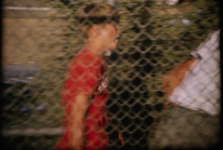Baseball players walk back and forth behind the fence