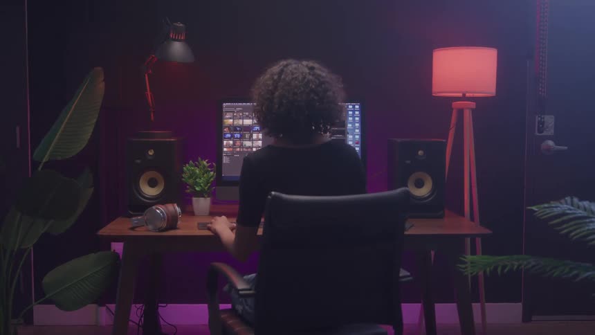A young woman using a desktop computer while seated indoors in a music studio