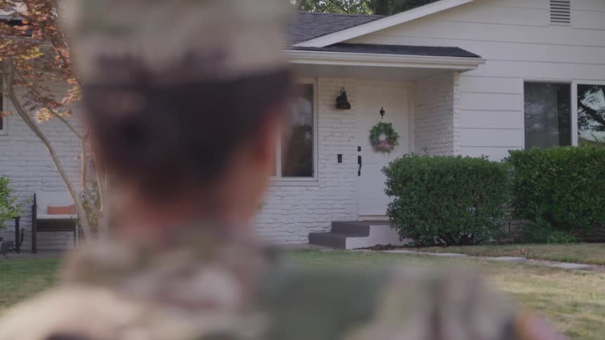 Military woman in uniform in front of a residential house