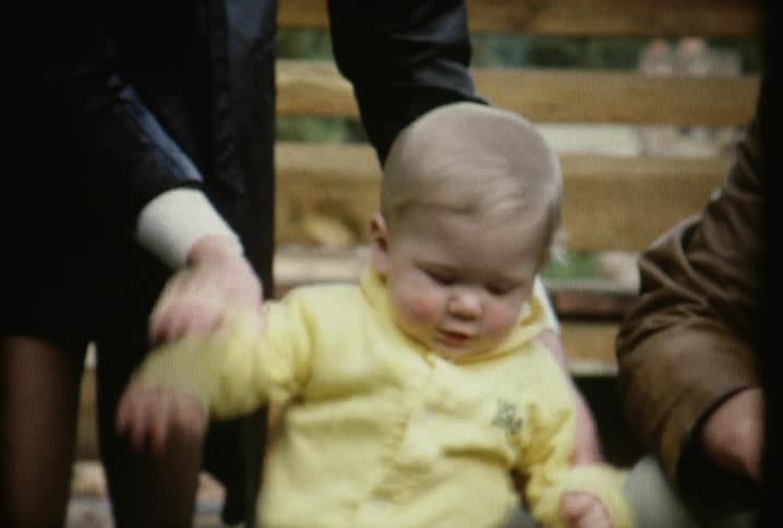 A woman claps a toddlers hands together and bounces it