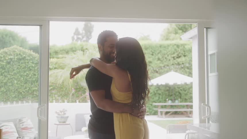 Happy couple slow dancing indoors near a large window