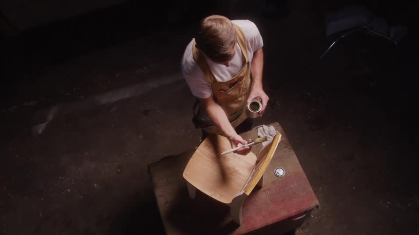 Carpenter varnishing a wooden chair