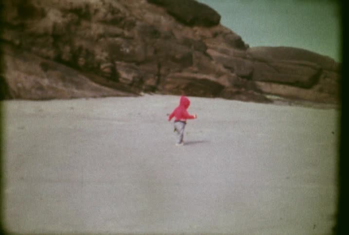 A baby is walking along the beach