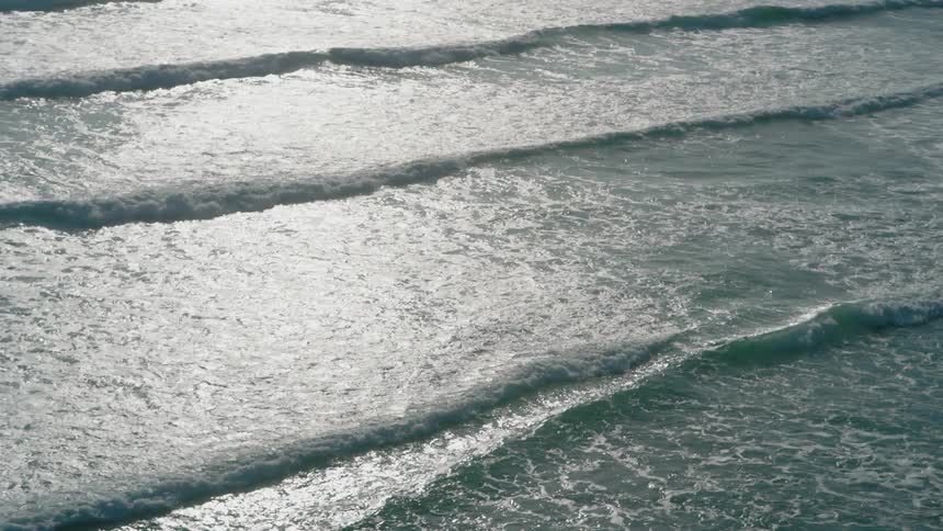 Aerial of low waves over a body of ocean water outdoors during daytime