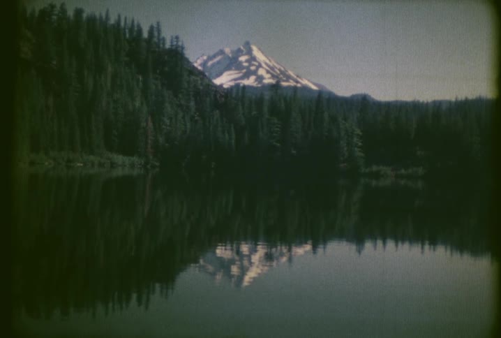 A lake surrounded by trees and a large mountain in the back