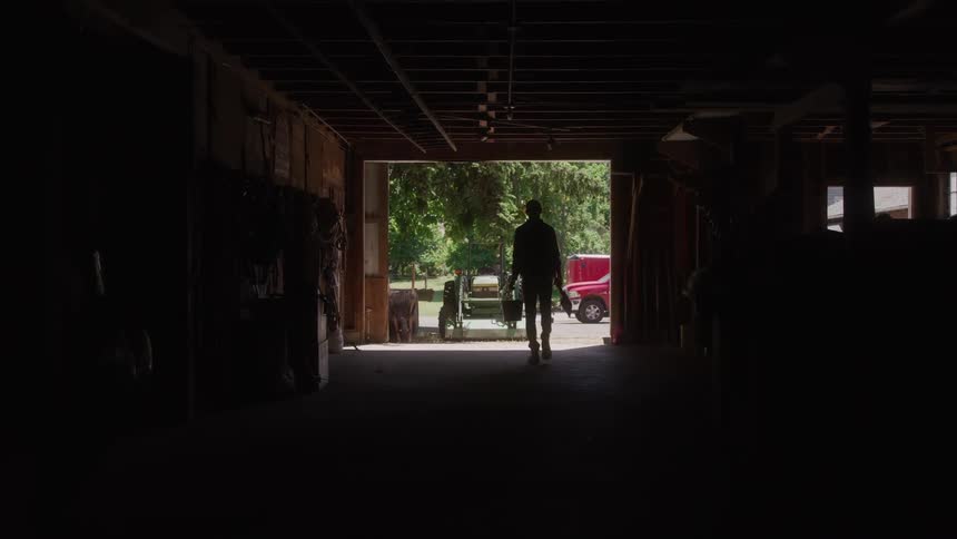 A man walks through a dark building and outdoors