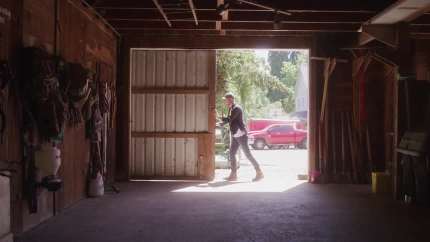 A man opening the garage door of a house at midday