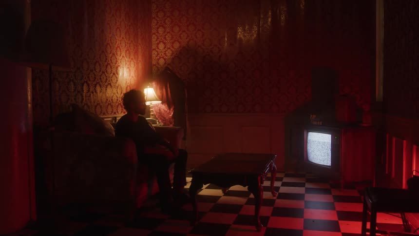 The man sits in front of the static filled television screen