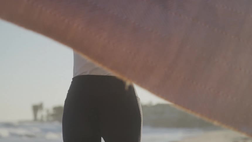 The woman lifts the blanket over her head on the beach