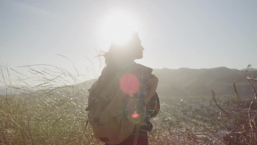 The woman shades her eyes from the sun on the mountain top