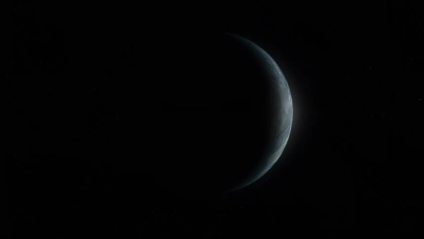 The dark side of earth in space is mostly in shadow with a small portion on the right illuminated by light