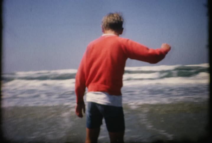 A boy slides on a board by the ocean