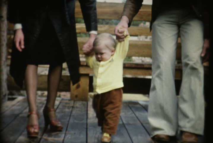 A boy is walking with two parents