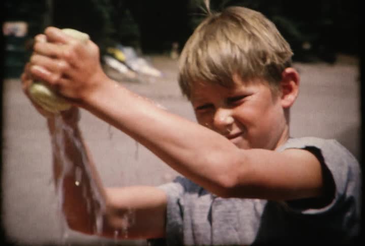 A boy wringing out a sponge from washing a wooden boat
