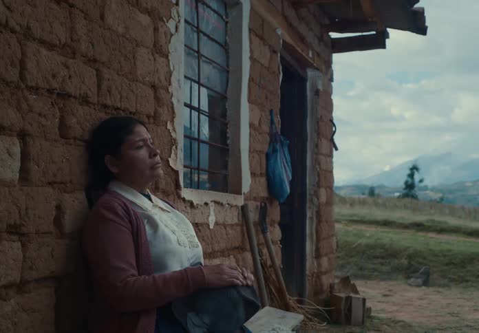 A woman is sitting outside her home