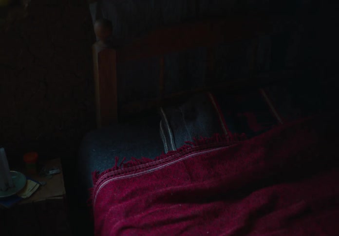The woman stands over her bed and walks away
