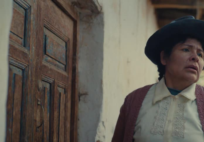 Woman with a braid and hat knocking on a wooden door