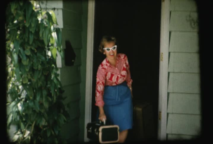 People exit a house holding luggage