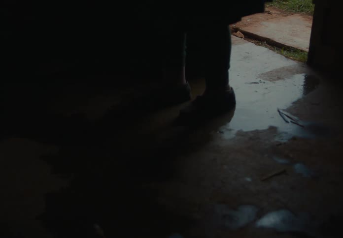 A female slowly walks into the pitch black room