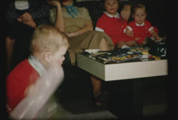 A child throwing a balloon in a house with his family around