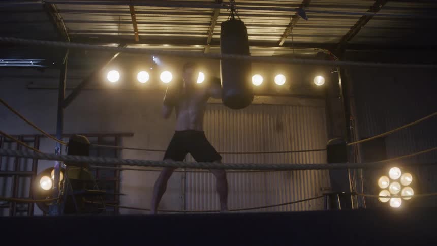 The man is punching the heavy bag in the ring