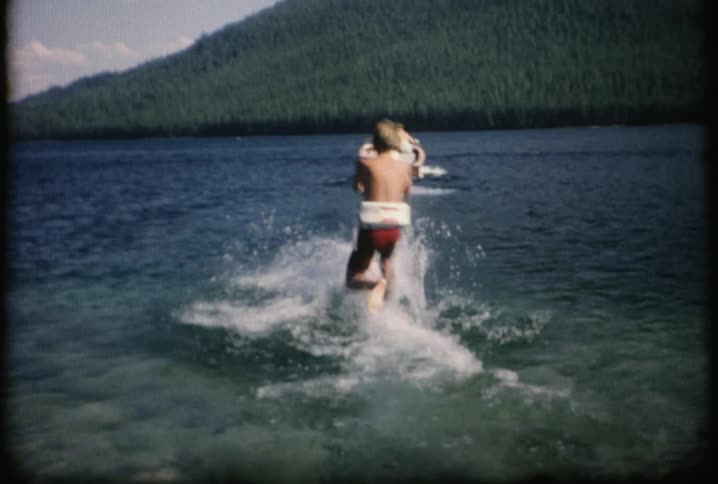 A young boy is pulled behind a boat on a rope