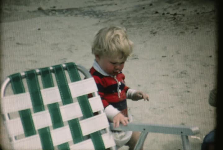 A baby walks along a beach chair