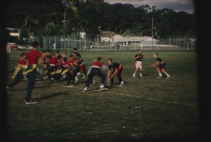 Flag football players run on a green field