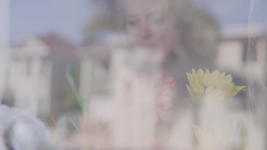 The florist is arranging flowers behind the window