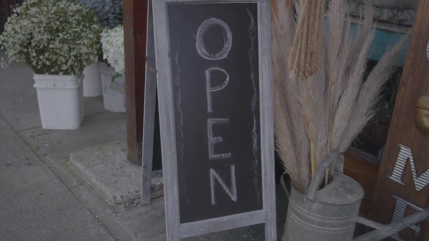 Open written on chalk board sign in front of flower store