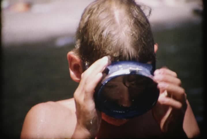 A boy puts on a round underwater mask