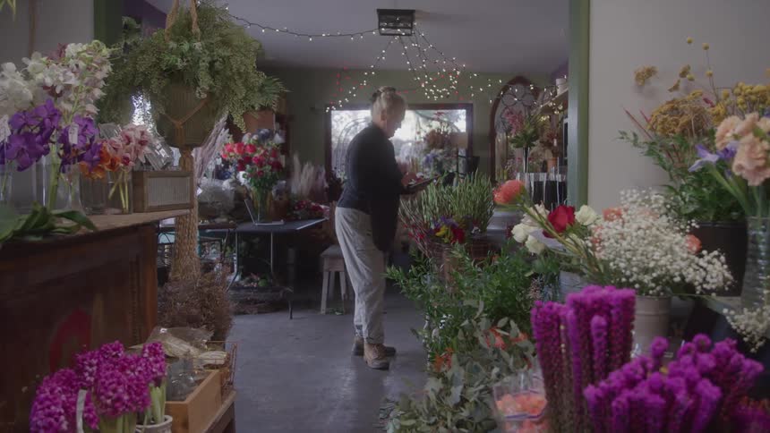 The worker is standing in the middle of the flower shop