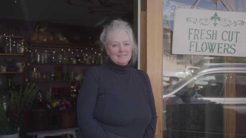 Woman smiling in front of a flower shop
