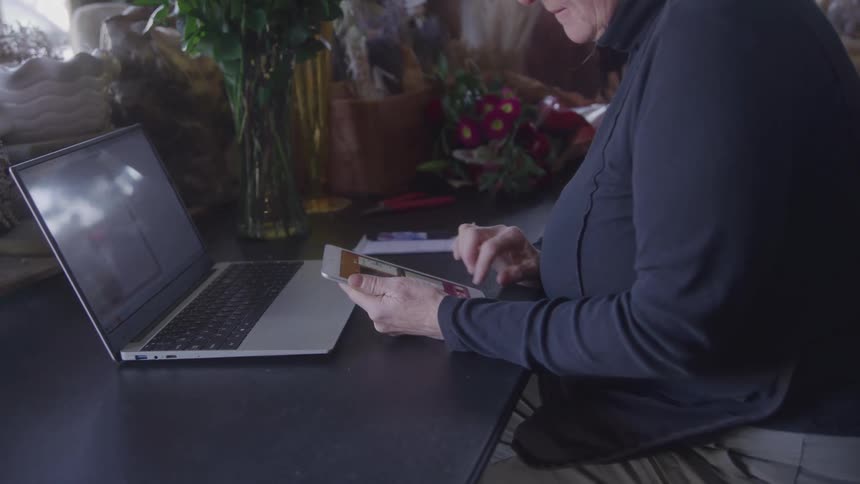 Person interacts with a tablet in front of a laptop in a flowerdecorated setting
