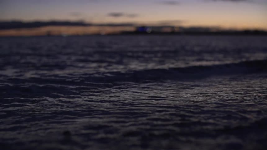 Waves crashing against a shore at sunset
