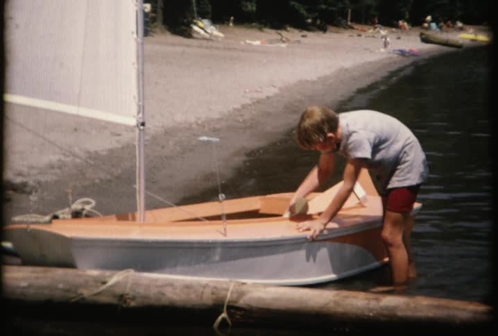A boy is cleaning a boat near the shore