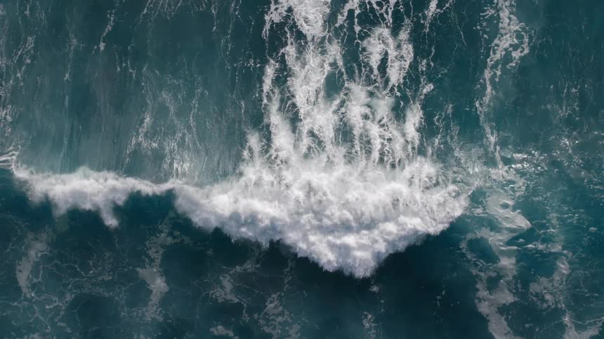 Wave crashing forcefully over the dark blue sea forming white foam in contrast with the water
