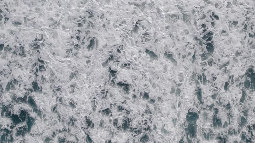 Waves crashing powerfully over the sea creating a thick layer of white foam