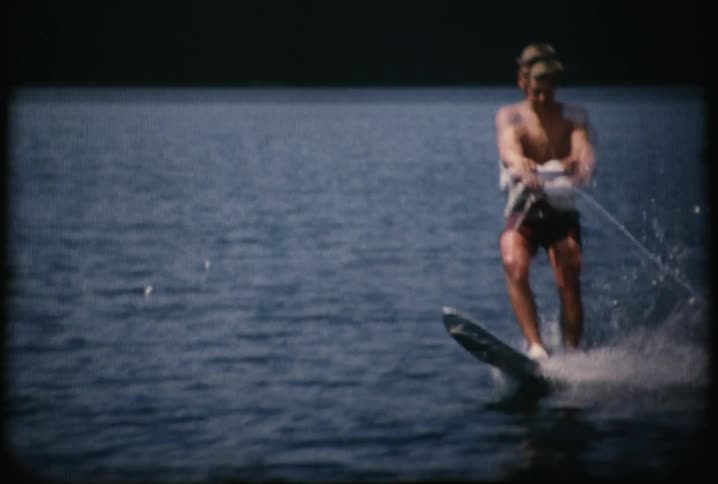 A boy is pulled behind a boat on a ski
