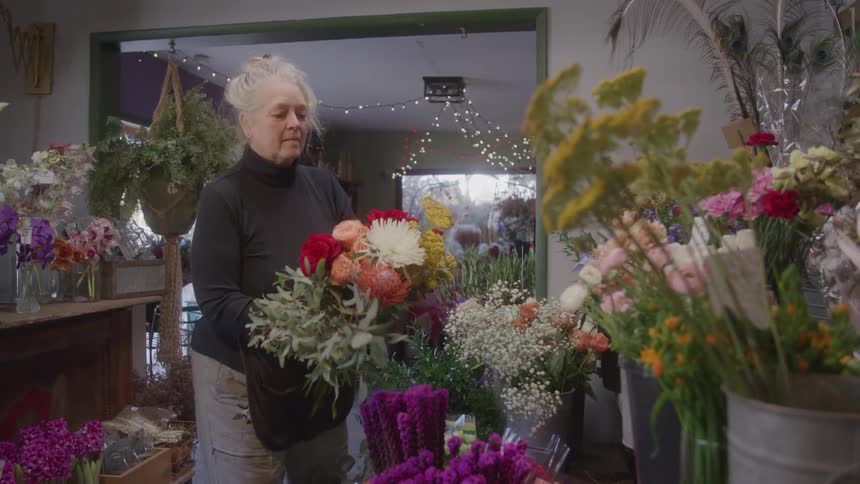 Woman arranging a flower bouquet in a flower shop decorated with lights