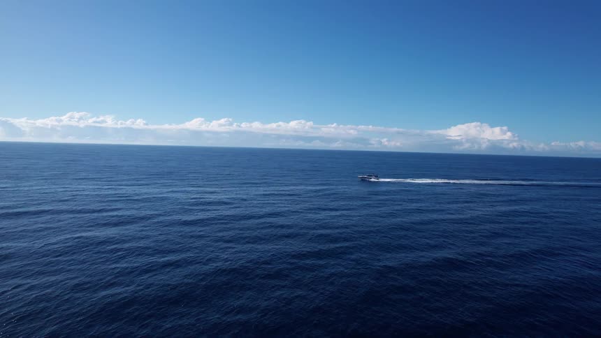 Boat travels across open water leaving a splashing trail behind