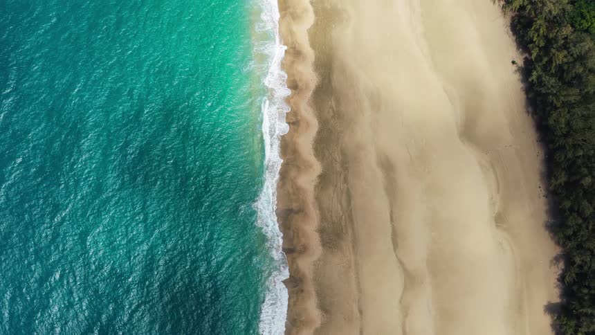 Ocean waves gently wash ashore along a stretch of sandy beach