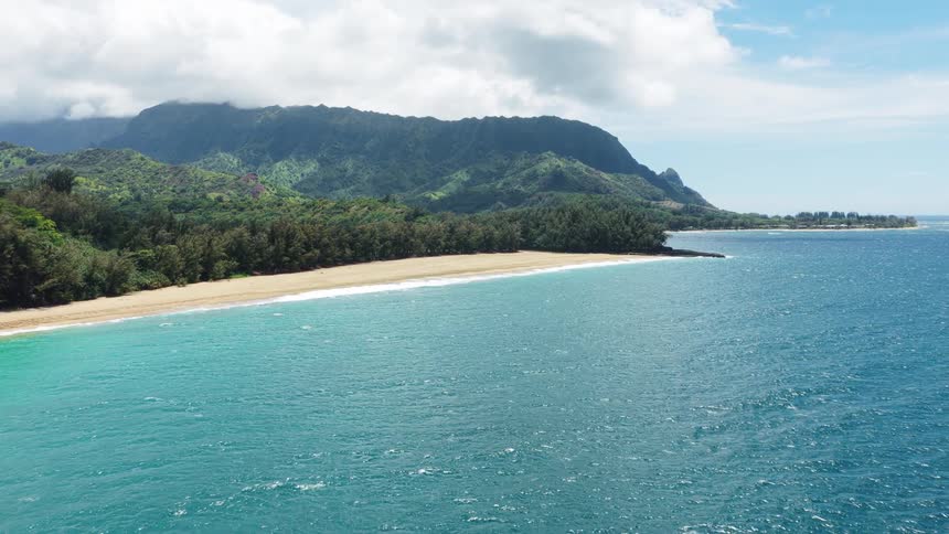 Secluded beach meets the vibrant blue sea in front of tropical mountains