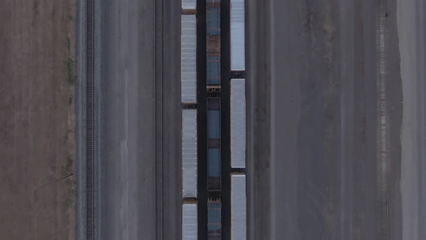 Aligned railcars occupy parallel tracks in an industrial yard seen from above