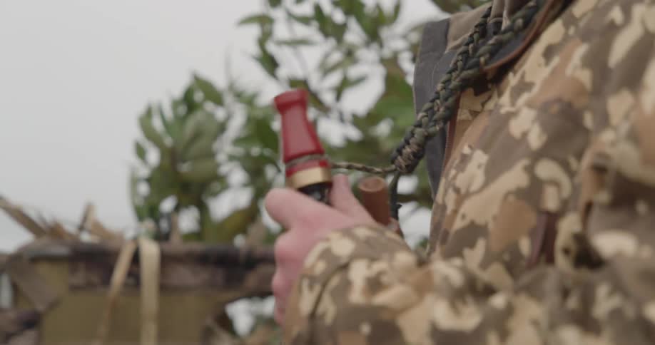 Person in military uniform holding an object on their body