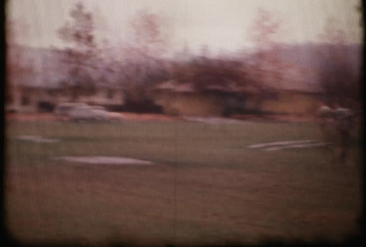 An old film of men playing football in a field or yard
