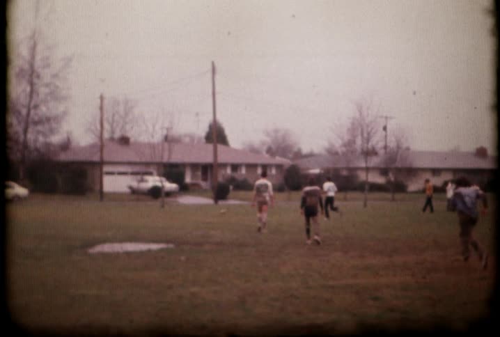 Football players are running down the field on a cloudy day