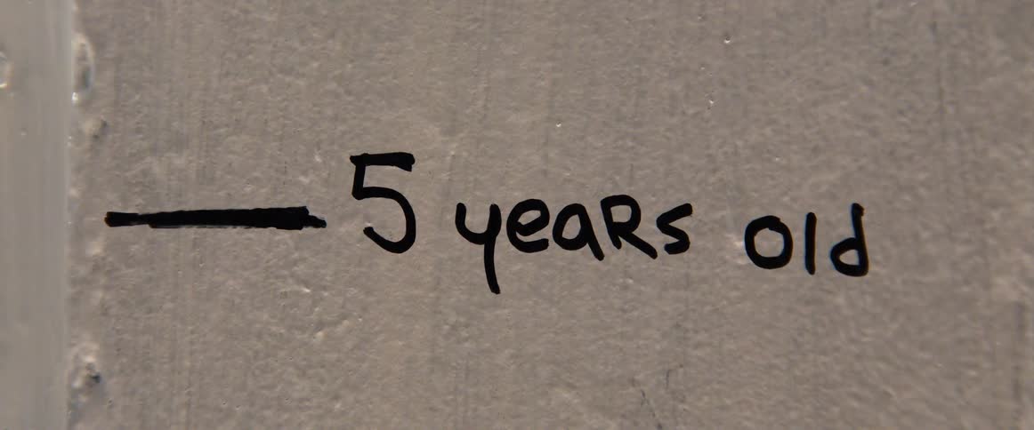 A wall marking shows the height of a child at 5 years old