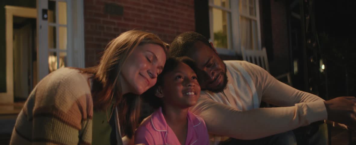 Woman man and child smiling together while sitting on the porch at night